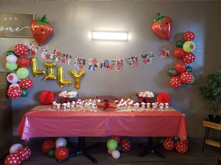 A strawberry themed birthday party with balloons and decorations at a lunch restaurant.