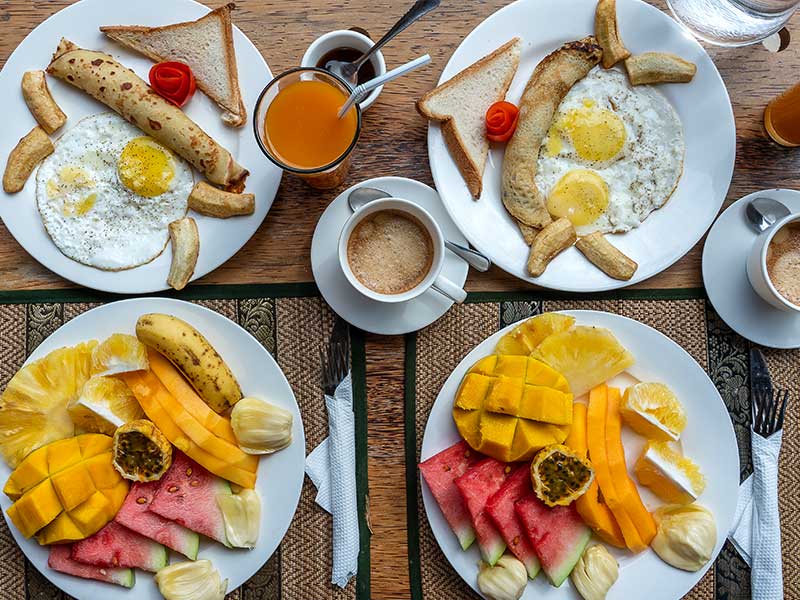 Four plates of Traditional breakfast food on a wooden table.